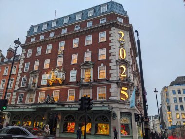 Londra, İngiltere - 1.18.2025: Piccadilly 'deki ikonik Fortnum ve Mason mağazası 2025 tabelasıyla aydınlatılmış, klasik görünüş ve saati bulutlu bir gökyüzüne karşıdır.