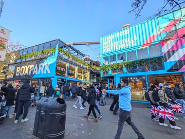 Londra, İngiltere - 11 Ocak 2025: İnsanlar açık bir günde kalabalık bir sokak yemeği ve perakende satış mağazası olan Boxpark Shoreditch 'in kendine özgü nakliye konteynır mimarisinin önünden geçtiler