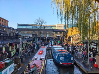 Londra, İngiltere - 1.11.2025: Regents Canal 'daki hareketli Camden Lock pazarında toplanan kalabalık, turne tekneleri gıda tezgahları ve tarihi binaların yanında kışın gökyüzü altında kenetlendi