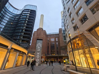 Londra, İngiltere - 2.9.2025: Yayalar, tarihi Art Deco ve modern mimarinin Alacakaranlık 'taki karşıtlığıyla Battersea Elektrik Santrali' nin yeniden geliştirilmiş alışveriş ve eğlence bölgesini keşfediyorlar