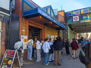 Londra, İngiltere - 3.29.2025: Ladbroke Grove metro istasyonunun tuğla girişinde toplanan yayalar, Londra 'nın kalabalık sokak yaşamı ortasında toplu taşıma sistemini gözler önüne seriyor