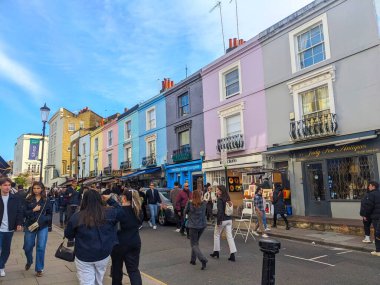 Londra, İngiltere - 29 Mart 2025: Parlak bir günde Notting Hill 'deki işlek Portobello Yolu boyunca canlı pastel renkli terasların ve evlerin önünden geçen yayalar