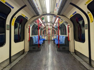 Londra, İngiltere - 11.9.2024: Simetrik perspektif görüntüsü klasik mavi moket koltukları ve kırmızı tırabzanları olan boş bir Londra metro vagonunda