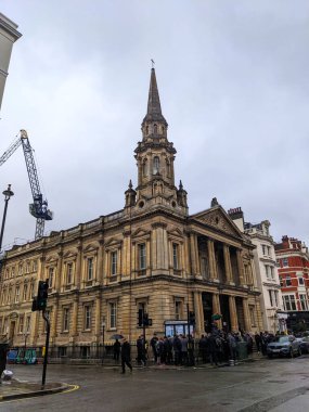 Londra, İngiltere - 3.30.2023: Marylebone 'da bulutlu bir günde, trafik ve yakınlarda bir vinç bulunan Hinde Caddesi Metodist Kilisesi' nin klasik cephesinin önündeki kaldırımda toplanan yayalar,