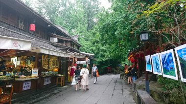 Chengdu, Çin - 30 Haziran 2018: Yayalar Kuanzhai Alley 'de geleneksel mimari ile canlı bir cadde keşfederler, Sichuan başkentinin tarihi kültürel bölgesindeki gür ağaçların altındaki bakkalları gezerler.