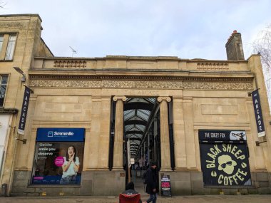 Bristol, İngiltere - 31 Ocak 2025: Yayalar Broadmead bölgesindeki tarihi bir alışveriş galerisi olan The Arcade 'nin neoklasik giriş cephesini bulutlu bir gökyüzünün altında geçtiler