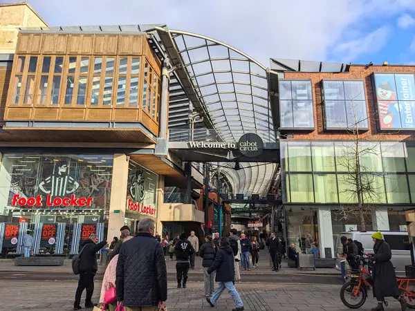 Bristol, İngiltere - 31 Ocak 2025: İnsanlar, Foot Locker gibi perakende mağazaları görünen modern bir şehir alışveriş merkezi olan Cabot Circus 'un girişindeki belirgin cam ve çelik çatı altında geziniyorlar