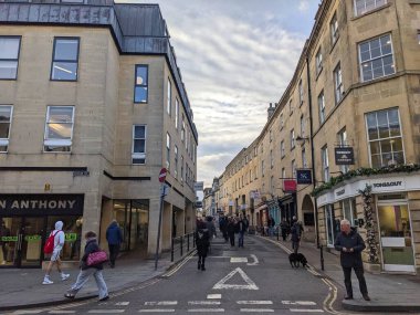 Bath, İngiltere - 30 Ocak 2025: İnsanlar, bulutlu bir gökyüzü altında geleneksel taş binalar ve dükkanlarla kaplı Yukarı Borough Duvarları boyunca yürüyüp, bu İngiliz şehrinin kentsel atmosferini yakalıyorlar.