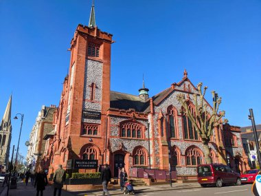 Londra, İngiltere - Nisan 07 2022: Pedestrianlar Muswell Hill, Londra 'daki çarpıcı Viktorya Dönemi Gotik Diriliş binasının yanından geçtiler.