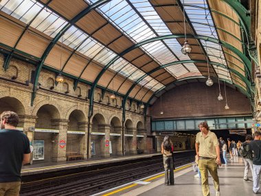 Londra, İngiltere - 02 Eylül 2022: İnsanlar Notting Hill Gate Metro istasyonunun klasik Viktorya dönemi mimarisinin altındaki platformda bekliyorlar
