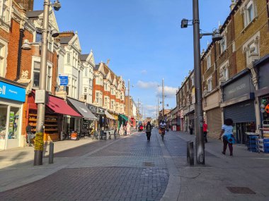 Londra, İngiltere - 19 Eylül 2021: Yayalar ve bisikletçiler, Walthamstow High Street 'te güneşli mavi gökyüzü altında tarihi teraslı binalar ve bağımsız dükkanlarla dolu canlı bir öğleden sonranın keyfini çıkarıyorlar.