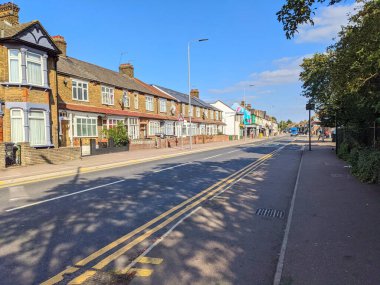 Londra, İngiltere - 20 Eylül 2021: Yerleşim yerleri ve yerel dükkanlar, insanların bir otobüs durağının yanında yürüdüğü ve beklediği canlı bir cadde.