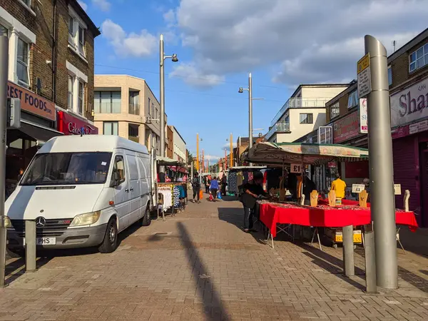 Londra, İngiltere - 19 Eylül 2021: Müşteriler ve satıcılar Londra 'da açık mavi bir gökyüzü altında mağazalarla dolu olan hareketli Walthamstow High Street' i çevreleyen renkli pazar tezgahlarında etkileşim halindeler