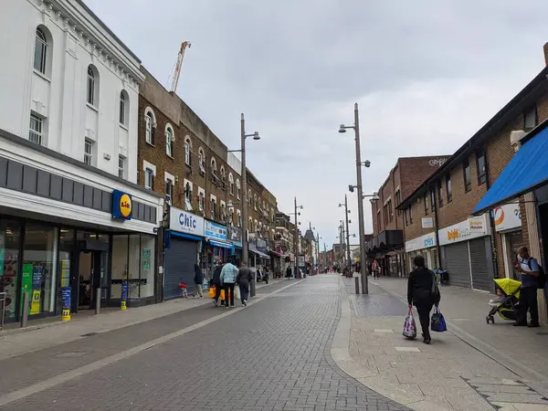 Londra, İngiltere - 18 Eylül 2021: Alışveriş poşetleri taşıyan ve Walthamstow High Street boyunca yürümeye zorlayan yayalar bulutlu bir gökyüzü altında mağazalar ve konut binalarıyla dolu