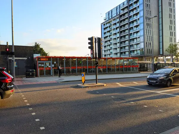 Londra, İngiltere - 20 Eylül 2021: Bir bisiklet parkı, yaya geçidi, çağdaş yapı ve öğleden sonra güneşinin sıcacık parıltısı altında geçen bir araba yakalayan modern şehir sokak sahnesi