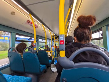 Londra, İngiltere - 16 Ekim 2021: Otobüsün kalabalık alt güvertesinde birkaç boş mavi koltuk ve sarı direklerle birlikte oturan yolcular