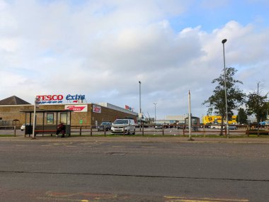 Londra, İngiltere - 16 Ekim 2021: Tottenham 'da işlek bir otoparkı ve bulutlu mavi gökyüzünün altındaki otobüs durağı ile birlikte bir Tesco Extra süpermarketi, kentsel perakende ve şehirdeki günlük yaşamı resmediyor.