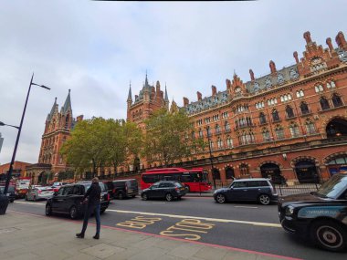Londra, İngiltere - Kasım 04 2021: Trafik ve yayalar bulutlu bir günde St Pancras Uluslararası İstasyonu ve St. Pancras Rönesans Oteli 'nin görkemli Viktorya dönemi Gotik cephesini geçti