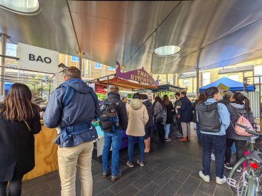 Londra, İngiltere - 24 Ekim 2021: Güneşli bir günde, canlı Greenwich Market 'te çeşitli sokak yemekleri satan yemek satıcılarından sabırla sipariş veren çeşitli müşteri grubu