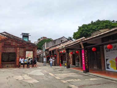 Taipei, Tayvan - 23 Kasım 2022: Ziyaretçiler Bopiliao Tarihi Bloğu 'nda bulutlu bir gökyüzü altında kırmızı fenerlerle süslenmiş büyüleyici sokakları ve yenilenmiş tuğla binaları keşfediyorlar