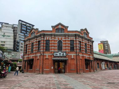 Taipei, Tayvan - 23 Kasım 2022: Tarihi Kızıl Ev Tiyatrosu, dükkanları ve bulutlu bir gökyüzünün altında yürüyen insanlarla dolu hareketli bir kültür merkezi olan Ximending bölgesinde yer alıyor.
