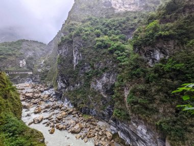 Taroko, Tayvan - 26 Kasım 2022: Liwu Nehri tarafından oyulmuş mermer kayalıklar, bulutlu bir gökyüzü altında Taroko Gorge Ulusal Parkı 'nın dramatik manzarasına hakim.
