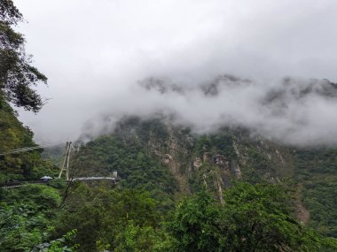 Taroko, Tayvan - 26 Kasım 2022: Sis ve bulutlar Taroko Boğazı 'nın dramatik uçurumlarını ve yemyeşil ormanlarını örterek Buluowan Askı Köprüsü' nü görünür hale getiriyor.