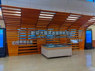Kaohsiung, Tayvan - 02 Aralık 2022: İngilizce ve Çince 'de göze çarpan bir hoş geldin işareti Kaohsiung Uluslararası Havalimanı' nın parlak, ferah terminalinde bir havaalanı modelinin üzerinde asılı duruyor.