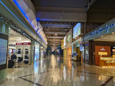 Kaohsiung, Tayvan - 02 Aralık 2022: Gezginler, gümrüksüz mağazalar ve yansıtıcı döşemelerle dolu modern Kaohsiung Uluslararası Havaalanı terminali koridorunda yürüyorlar
