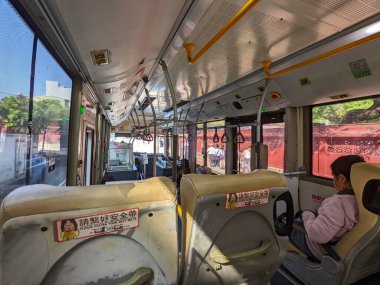 Tainan, Tayvan - 01 Aralık 2022: Yolcuları, koltukları, tırabzanları gösteren bir kamu otobüsünün içine bakın ve gündüz vakti sokağa bir göz atın.