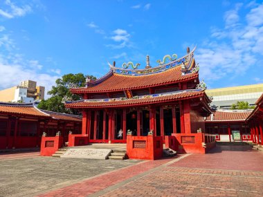 Tainan, Tayvan - 02 Aralık 2022: Canlı kırmızı duvarlar ve parlak mavi gökyüzü altındaki tarihi Tainan Konfüçyüs Tapınağı 'nın süslü çatısı