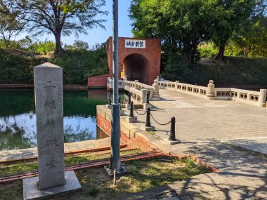 Tainan, Tayvan - 01 Aralık 2022: Sonsuz Altın Kale 'nin ikonik kırmızı tuğla kemer ve taş köprüsü, Erkunshen Bataryası olarak da bilinir, hendeğe yansıyan parlak mavi bir gökyüzünün altında durmaktadır.