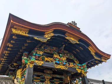 Kyoto, Japonya - 14 Aralık 2023: Anka kuşları ve ejderhaların yer aldığı süslü altın detaylar ve karmaşık oymalar Nishi Hongwanji-ji kapı girişinin tarihi ahşap yapısını süslüyor