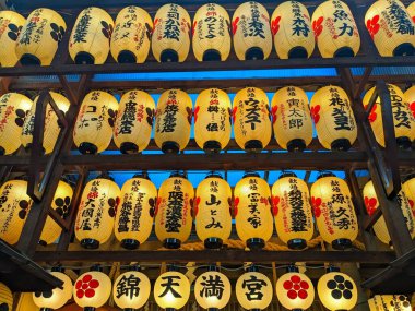 Kyoto, Japonya - 14 Aralık 2023: Siyah kaligrafi ve kırmızı sembollerle süslenmiş parlak Japon çene fenerleri geceleyin Nishiki Tenmangu 'da asıldı