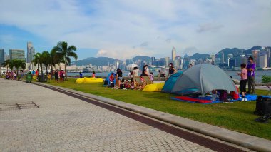 Hong Kong - 27 Ağustos 2021: Gruplar, Batı Kowloon Sanat Parkı 'nın yanındaki çimenli bir alanda dinleniyor ve piknik yapıyorlar.