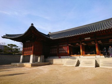 Seul, Güney Kore - Şubat 04 2019: Gyeongbokgung Sarayı 'nda Jangandang manzarası Tahta yapılar ve kiremitli çatılar berrak mavi gökyüzü altında gezen ziyaretçiler