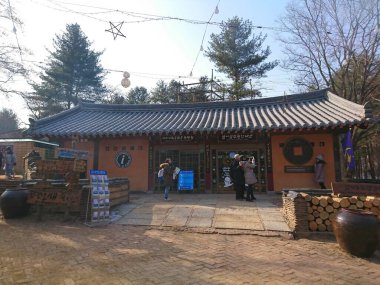 Namiseom, Güney Kore - Şubat 05 2019: Geleneksel Nami Adası Bilgi Merkezi binasının önünde toplanan ziyaretçiler, parlak bir kış gününde fotoğraf çekiyor ve tabela okuyorlar