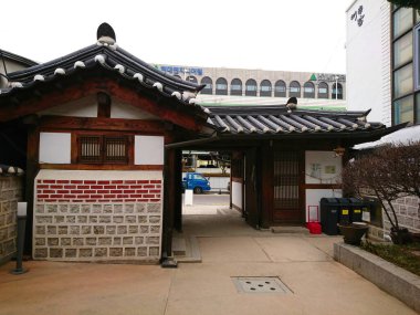 Seul, Güney Kore - Şubat 06 2019: Bukchon Hanok Villa 'daki Bukchon Geleneksel Kültür Merkezi' nin girişi seramik çatı ve taş duvarlarla modern şehir manzarasının yanında yer alıyor.