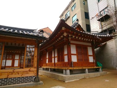 Seul, Güney Kore - Şubat 06 2019: Bukchon Hanok Villa 'sındaki Bukchon Geleneksel Kültür Merkezi' nde modern kentsel binaların yanında fayanslı çatıları olan geleneksel Kore Hanok ahşap evleri bulunuyor