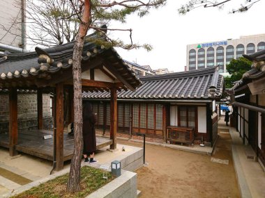 Seul, Güney Kore - Şubat 06 2019: Bukchon Hanok Villa 'daki Bukchon Geleneksel Kültür Merkezi' nde çatı döşemeli ve ahşap detaylı geleneksel Hanok evlerini gören bir kişi görülüyor