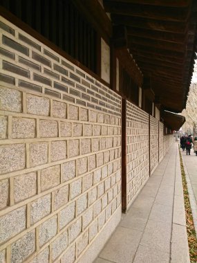 Seul, Güney Kore - Şubat 06 2019: Yayalar Unhyeongung 'un geleneksel mimarisi ve dokulu taş blokları ile uzun tarihi bir duvarın yanında yürüyorlar