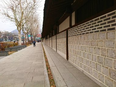 Seul, Güney Kore - Şubat 06 2019: Yayalar, şehrin işlek şehir merkezinde sakin bir kış gününde geleneksel taş duvar ve Unhyeongung cephesi boyunca yürüyorlar.