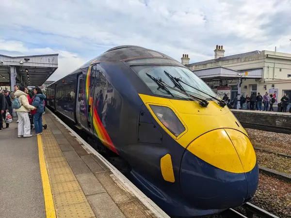 Canterbury, İngiltere - 19 Nisan 2025: Gökkuşağı üniformalı yüksek hızlı bir Javelin treni bulutlu bir gökyüzü altında yolcu beklerken Canterbury Batı İstasyonu platformunda duruyor