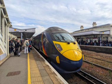 Canterbury, İngiltere - 19 Nisan 2025: Güneydoğu Demiryolu 'nun modern yüksek hızlı treni olarak yoğun platformdan ayrılan yolcular Canterbury Batı İstasyonu' na belirgin bir gökkuşağı çizgisi ile geldiler
