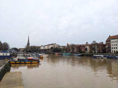 Bristol, İngiltere - 29 Ocak 2025: Dar kayıklar ve renkli evler, ikonik St Mary Redcliffe kulesiyle tarihi Bristol Limanı 'nı kaplıyor.