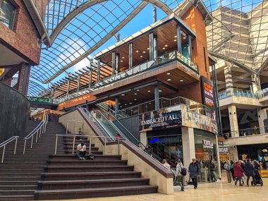 Bristol, İngiltere - 31 Ocak 2025: Müşteriler ve ziyaretçiler Cabot Circus alışveriş merkezinin çağdaş çok katlı iç mekanında büyük cam bir çatı altında merdivenleri ve yürüyen merdivenleri kullanıyorlar