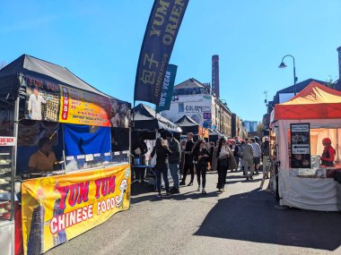 Londra, İngiltere - Nisan 06 2025: İnsanlar yiyecek tezgahlarına göz atıyor ve Shoreditch East London 'daki Brick Lane' deki canlı bir sokak pazarında yürüyorlar.