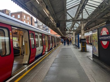 Londra, İngiltere - 26 Nisan 2025: Hammersmith ve City Line 'ın ikonik kırmızı ve beyaz bir Londra metro treni Hammersmith istasyonunda yolcu bekliyor.