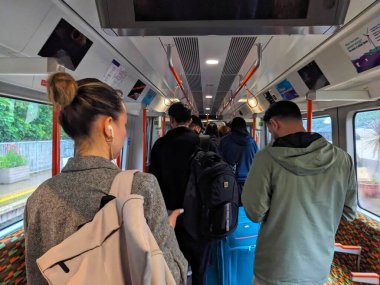 Londra, İngiltere - 21 Mayıs 2024: Modern bir Londra metro vagonunu boşaltıp terk eden yolcular, tren arızalandıktan sonra yağmurlu bir platforma bakarak saatlerce raylarda mahsur kaldılar