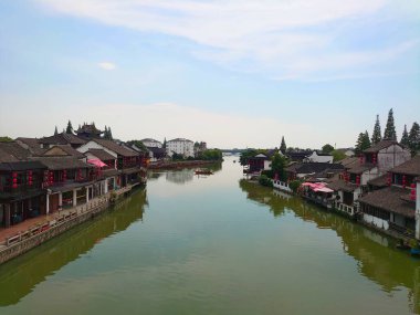 Zhujiajiao, Çin - 25 Temmuz 2019: Geleneksel deniz kenarı binaları, Zhujiajiao Antik Kenti 'nde sakin bir kanalı çevreleyen, gondol tarzı botların resimli sahneyi yansıttığı bir kanal.